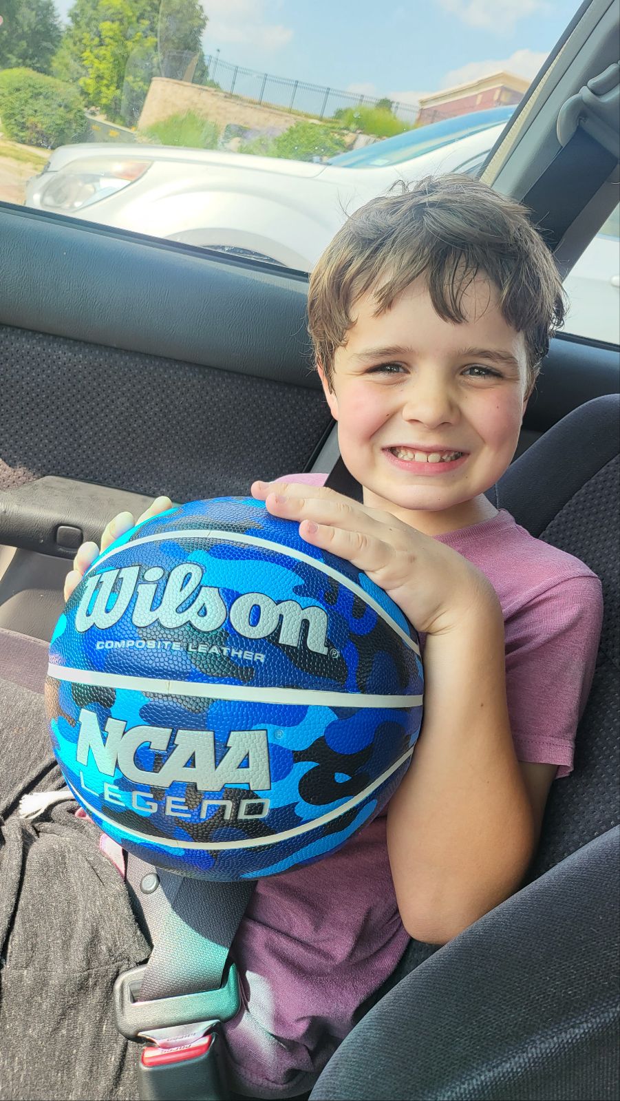 boy posing with his new blue basketball