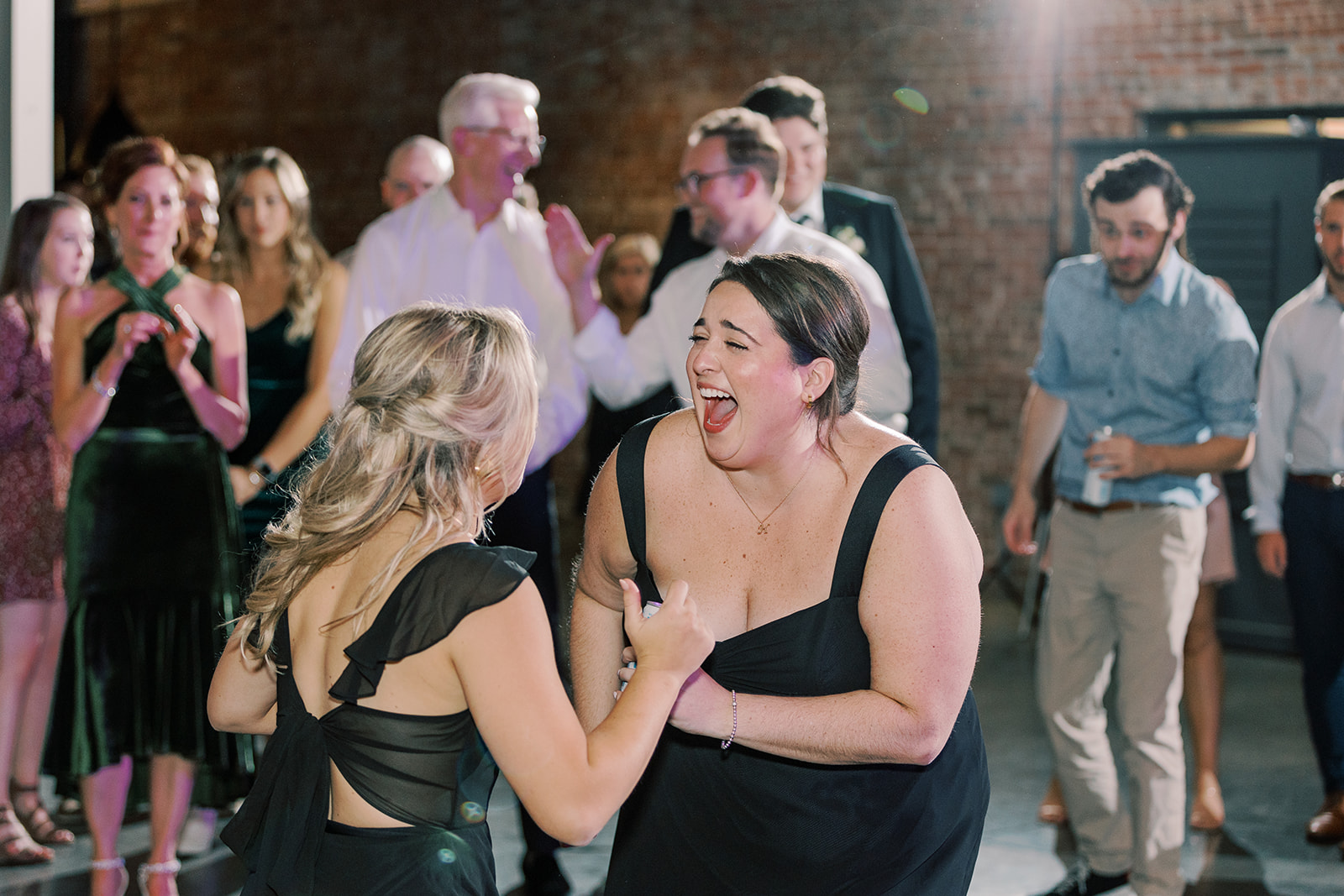Bridesmaids screaming in delight while dancing during wedding celebration